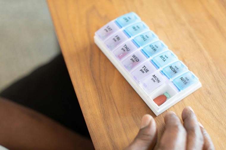 A weekly pill organizer on a wooden table